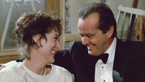 Meryl Streep and Jack Nicholson in Heartburn. A white woman with dark hair and a white man in a tuxedo face each other, smiling.
